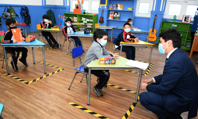 Salón de clases con niños usando mascarilla y manteniendo una distancia segura.